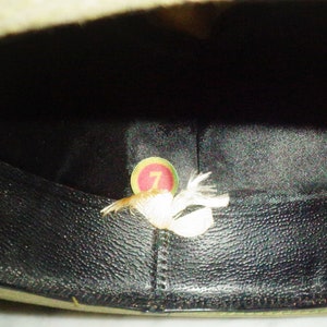 May include: The inside of a green felt hat with a black leather band. A small white tag with the number "7" is visible inside the hat.