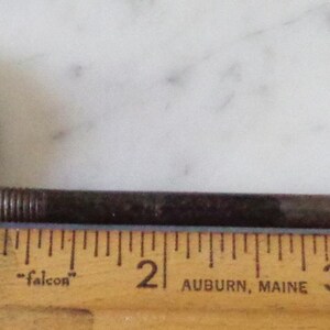 May include: A vintage metal knob with a red and white flower design and a matching metal rod. The rod is about 3 inches long.