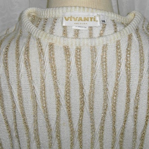 May include: White sweater with gold stripes. The sweater has a crew neck and is made of a soft, knit fabric. The label reads "VIVANTL. Made in U.S.A."