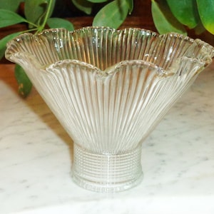 May include: A clear glass bowl with a fluted design and a scalloped rim. The bowl has a short, cylindrical base.