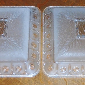 May include: Two frosted glass ceiling light fixtures with a square shape and a decorative pattern. The fixtures have a frosted glass center with a square design and a decorative border.