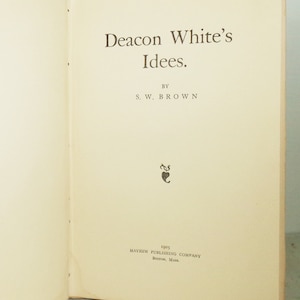 May include: Open book with the title "Deacon White's Idees" by S.W. Brown. The text is in a serif font, printed in brown ink on aged, cream-colored paper. The book was published in 1905 by Mayhew Publishing Company, Boston, Mass.