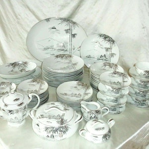 Puede incluir: Un juego completo de vajilla de porcelana blanca con un diseño japonés inspirado en la tinta negra y el oro, que representa bambú y paisajes montañosos.