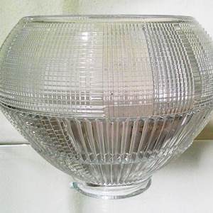 May include: A clear glass bowl featuring a textured grid pattern on the upper half and vertical fluted ridges on the lower half. The bowl has a rounded, bulbous shape with a wide opening at the top and a small, circular base at the bottom.