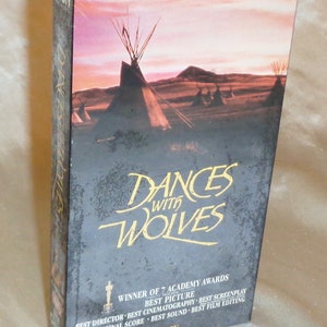 May include: A VHS tape case for the movie Dances with Wolves. The case features a sunset scene with teepees in the foreground and the movie title in gold lettering. The text "Winner of 7 Academy Awards" is printed on the bottom of the case.