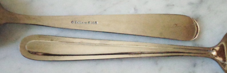 May include: Two silver spoons with a simple design. The spoon on top has the inscription "&copy;Talien Silver" on the back.