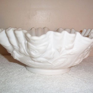 Peut inclure: Un bol en verre de lait blanc avec un bord festonné et un motif floral. Le bol est en verre blanc opaque et a une finition lisse et brillante.