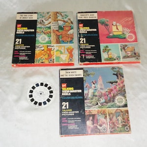 May include: A collection of vintage View-Master reels, including "The True Story of Smokey Bear," "Snoopy and the Red Baron," and "Snow White and the Seven Dwarfs." Each box contains 21 talking pictures. A single View-Master reel is also included. The boxes are red, black, and white.
