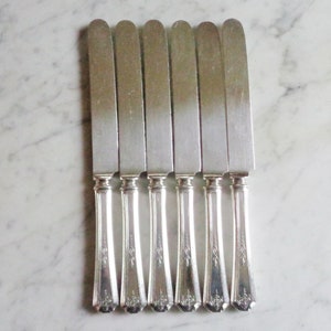 May include: Set of seven silver butter knives with ornate handles.