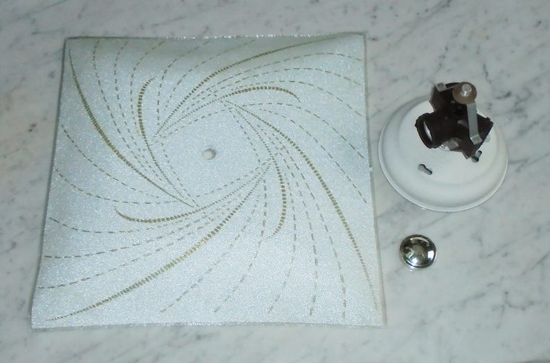 Pode incluir: Lumin&aacute;ria de teto branca com um padr&atilde;o de espiral em dourado e branco. A lumin&aacute;ria tem uma cobertura de pl&aacute;stico branco e uma base de metal.