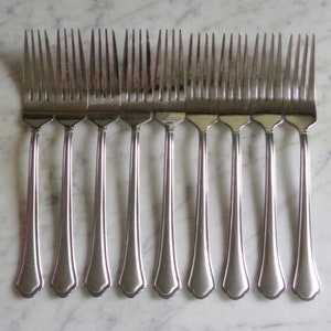 May include: A set of ten silver forks with ornate handles. The forks are arranged in a row, with the handles facing the viewer.