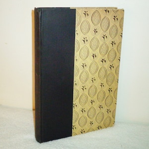 May include: A black hardcover book with a gold patterned spine. The pattern features stylized leaves and circles.
