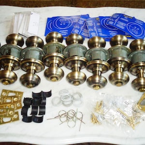 以下が含まれることがあります： 鍵穴付きのアンティークブラス製のドアノブ8個セット。ストライクプレート、ネジ、その他の取り付け部品など、さまざまな金具が付属しています。