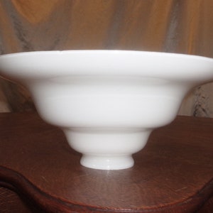 May include: White glass lampshade with a wide, flared top and a narrow base. The lampshade is made of smooth, opaque glass.