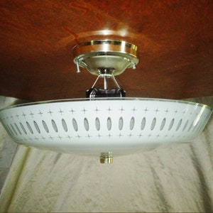 May include: A white ceiling light fixture with a frosted glass shade featuring a geometric pattern of circles and stars. The fixture has a chrome finish and a simple design.