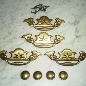 Puede incluir: Cuatro tiradores de armario de latón antiguo con diseños ornamentados y un juego de cuatro tornillos de latón. Los tiradores tienen un diseño de hoja decorativo y una manija curva.