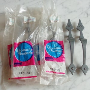 May include: Two silver-toned decorative door handles with a pointed design. The handles are packaged in clear plastic bags with pink and blue labels that read "Decorative Hardware" and "Ward" with the product number "84-9-918".