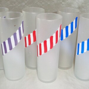 May include: Six frosted glass tumblers with a white and colored stripe design. The stripes are red and white, purple and white, and blue and white.