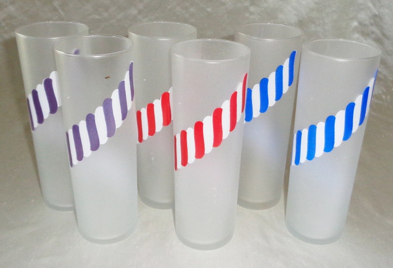 May include: Six frosted glass tumblers with a white and colored stripe design. The stripes are red and white, purple and white, and blue and white.