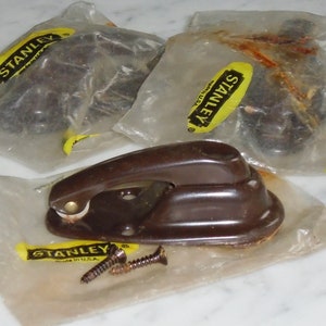 May include: Three packages of brown plastic window latches with screws. Each package has a yellow label with the text "STANLEY Made in U.S.A."
