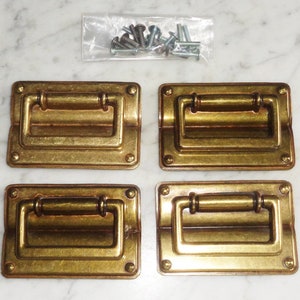 May include: Four antique brass drawer pulls with a rectangular shape and a rounded handle. The pulls have a slightly distressed finish, giving them a vintage look.