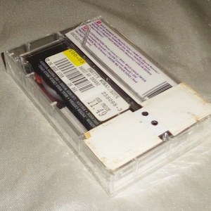 Może przedstawiać: Przezroczysty plastikowy futerał na kasetę z białą etykietą. Etykieta zawiera czarny tekst: "Pretty Woman/SDTK 258098-3 Our Price 11.49".