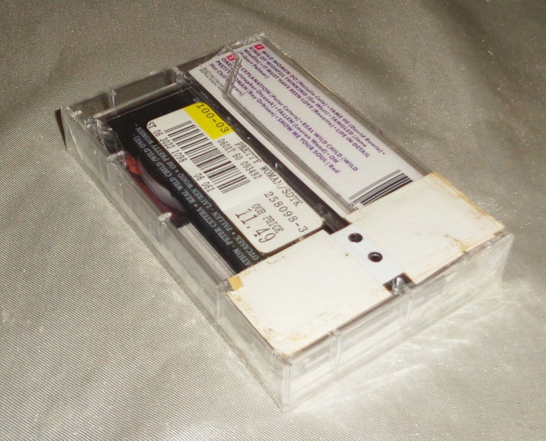 Może przedstawiać: Przezroczysty plastikowy futerał na kasetę z białą etykietą. Etykieta zawiera czarny tekst: "Pretty Woman/SDTK 258098-3 Our Price 11.49".