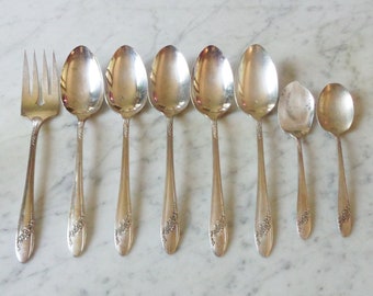 May include: Set of eight silver-plated spoons and a fork with an ornate floral design. The spoons are various sizes, including a small spoon and a larger serving spoon.