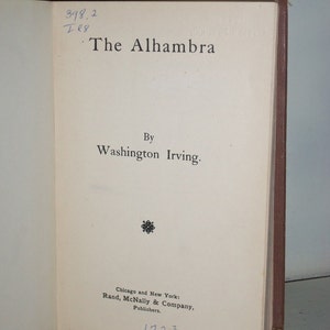 May include: A vintage book titled "The Alhambra" by Washington Irving. The book was published in 1923 by Rand, McNally & Company.