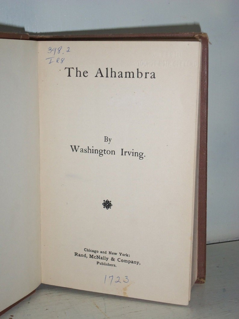 May include: A vintage book titled "The Alhambra" by Washington Irving. The book was published in 1923 by Rand, McNally & Company.