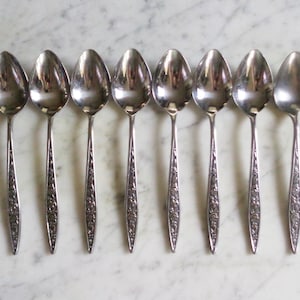 May include: Set of eight silver teaspoons with an ornate floral design on the handle.