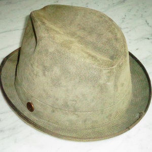 May include: A green felt fedora hat with a brown band and a brass button.