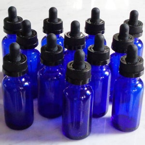 May include: A collection of twelve cobalt blue glass bottles with black dropper tops. The bottles are arranged in three rows of four.