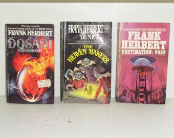 May include: Three vintage science fiction books by Frank Herbert. Titles include "The Dosadi Experiment," "Dune: The Heaven Makers," and "Destination: Void." The covers feature colorful illustrations and text.