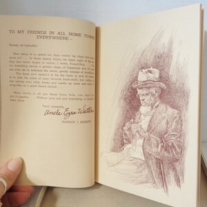 May include: A vintage book with a brown cover and a handwritten dedication to friends in all hometowns. The text reads "To my friends in all hometowns everywhere - Howdy ev'vybuddy". The book is open to a page with a black and white illustration of a man in a hat and coat, sitting and holding a small object in his hands.