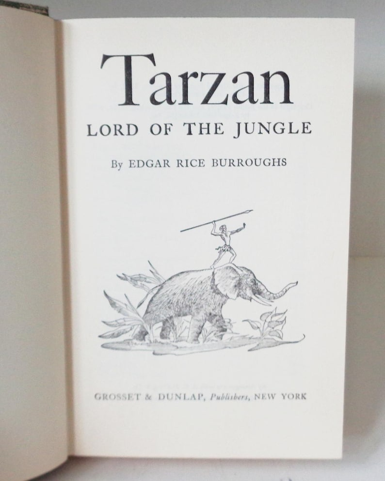 May include: A black and white illustration of Tarzan riding an elephant through the jungle. The book cover features the title "Tarzan, Lord of the Jungle" by Edgar Rice Burroughs and the publisher "Grosset & Dunlap, Publishers, New York".