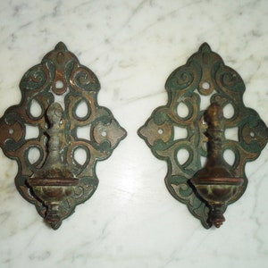 May include: Two ornate, decorative wall hooks with a green and copper finish. Each hook features a detailed, intricate design with a scrollwork pattern.
