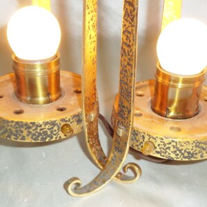 May include: A pair of antique gold-toned metal table lamps with clear glass bulbs. The lamps have a decorative, ornate design with a textured finish.