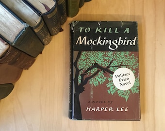 May include: A vintage paperback copy of "To Kill a Mockingbird" by Harper Lee. The book cover features a stylized illustration of a tree with green leaves against a brown background. The text "Pulitzer Prize Novel" is in a white circle on the cover.