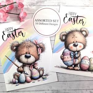 May include: Two Easter greeting cards featuring adorable teddy bears. One bear holds a paintbrush, the other an Easter egg. The cards have the text "Happy Easter" and a rainbow background. The set includes 10 different designs.