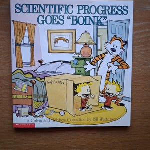 May include: A book cover featuring a cartoon scene from "Calvin and Hobbes." The title "SCIENTIFIC PROGRESS GOES 'BOINK'" is displayed above an illustration of Calvin, Hobbes, and a cardboard box. The book is a "Calvin and Hobbes Collection" by Bill Watterson.