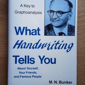 May include: A white book cover titled A Key to Graphoanalysis: What Handwriting Tells You About Yourself, Your Friends, and Famous People by M. N. Bunker. The cover features a blue-toned portrait of a man wearing glasses in a rectangular frame.