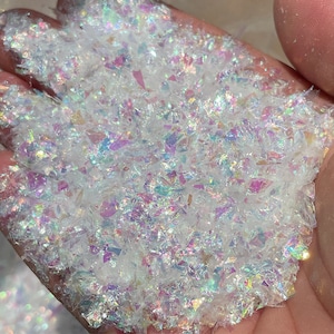 Op de afbeelding: Een close-up van iriserende witte glittervlokken, perfect om glans toe te voegen aan knutselprojecten en harsprojecten.