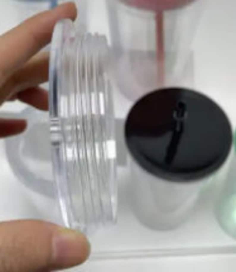 Pu&ograve; includere: Primo piano di un coperchio in plastica trasparente con un coperchio nero in cima. Il coperchio ha una superficie testurizzata ed &egrave; progettato per un bicchiere.