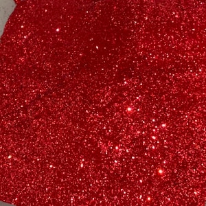 May include: A close-up of red glitter. The glitter is very fine and has a sparkly finish.