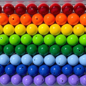 May include: A rainbow of colorful round beads, starting with red and ending with purple. The beads are arranged in rows, creating a vibrant and colorful pattern.