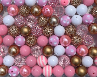 May include: A collection of pink, white, and gold beads. The beads vary in size, texture, and design, including solid colors, polka dots, stripes, and crystal embellishments. Some beads have a pearlescent finish, while others are metallic.