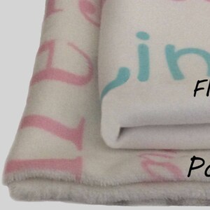 May include: Three different types of blankets: a white jersey knit blanket, a white fleece blanket with pink and blue lettering, and a white posh blanket with pink lettering.