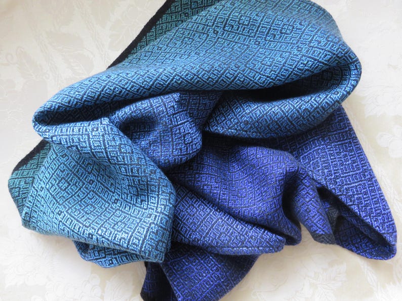 以下が含まれることがあります： 青色の濃淡で表現された、幾何学的なひし形模様の織物。 柔らかく、表面にテクスチャがあります。 色の範囲は、明るいティールから深いインディゴまでで、レイヤー効果を生み出しています。