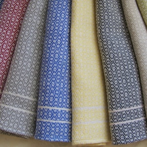 May include: A set of eight kitchen towels in various colors, including blue, red, gray, yellow, and green. The towels have a diamond pattern and white borders.